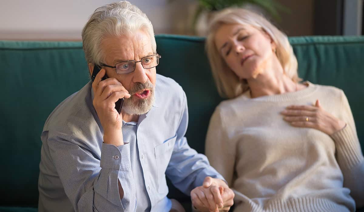 An image of someone ringing emergency services with another person very pale and unconscious