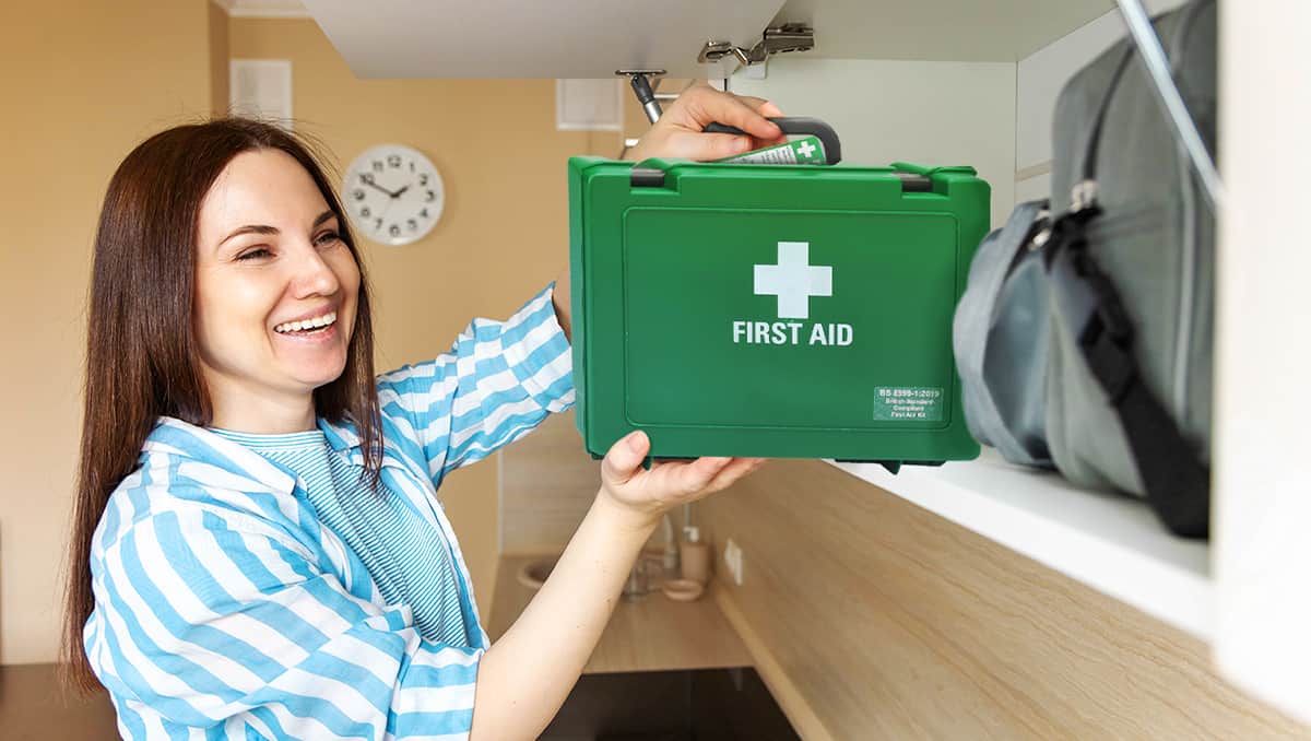 Woman taking a first aid kit out of a storage area at home