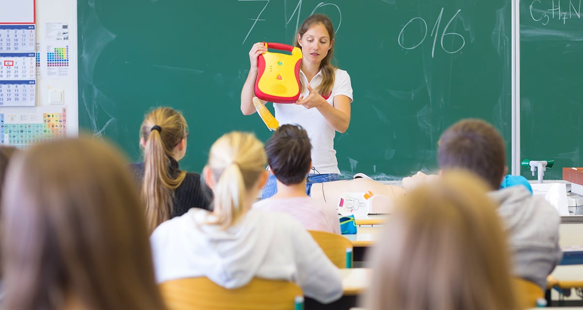 A teacher showing her students what a defibrillator looks like and how to use one