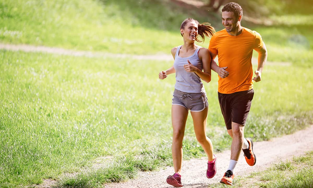 Man and woman go for a run together on a trail outdoors