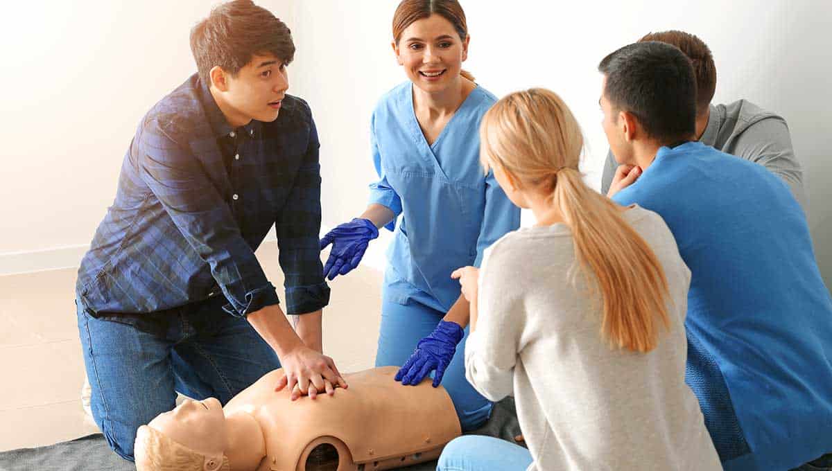 Someone training to perform CPR by administering compressions to a CPR manikin