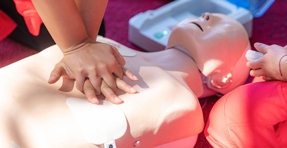 Instructor performing CPR on a manikin to demonstrate to students