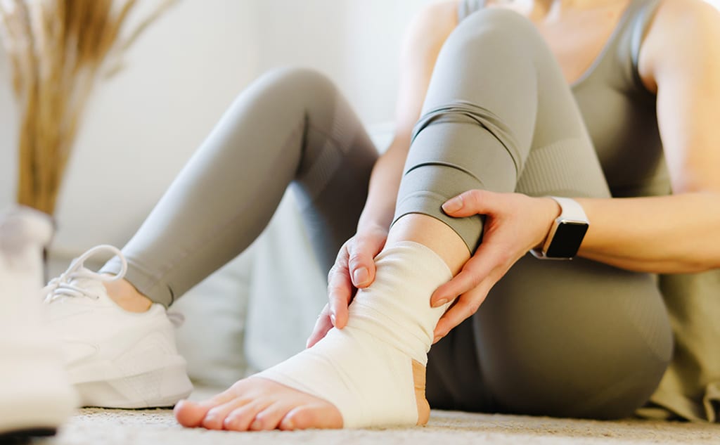 A runner wraps a minor foot sprain in a conforming bandage for compression