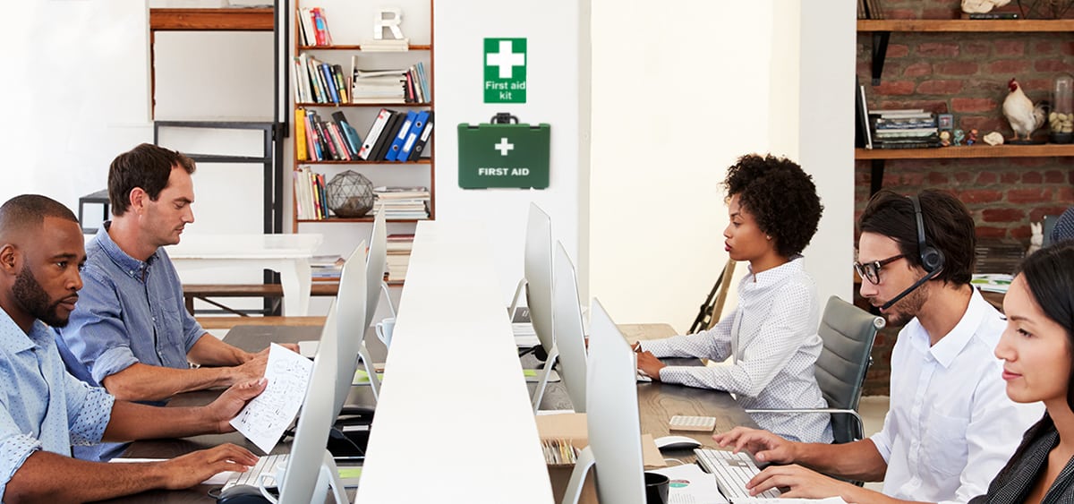 Office employees working with a first aid kit mounted on the wall