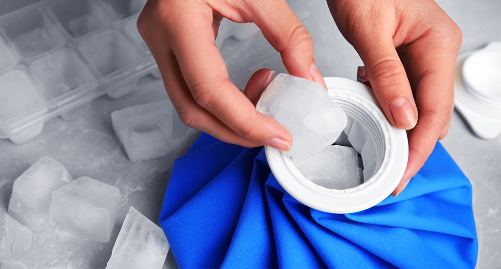 Someone filling up a reusable ice bag with ice cubes for use in cold therapy.