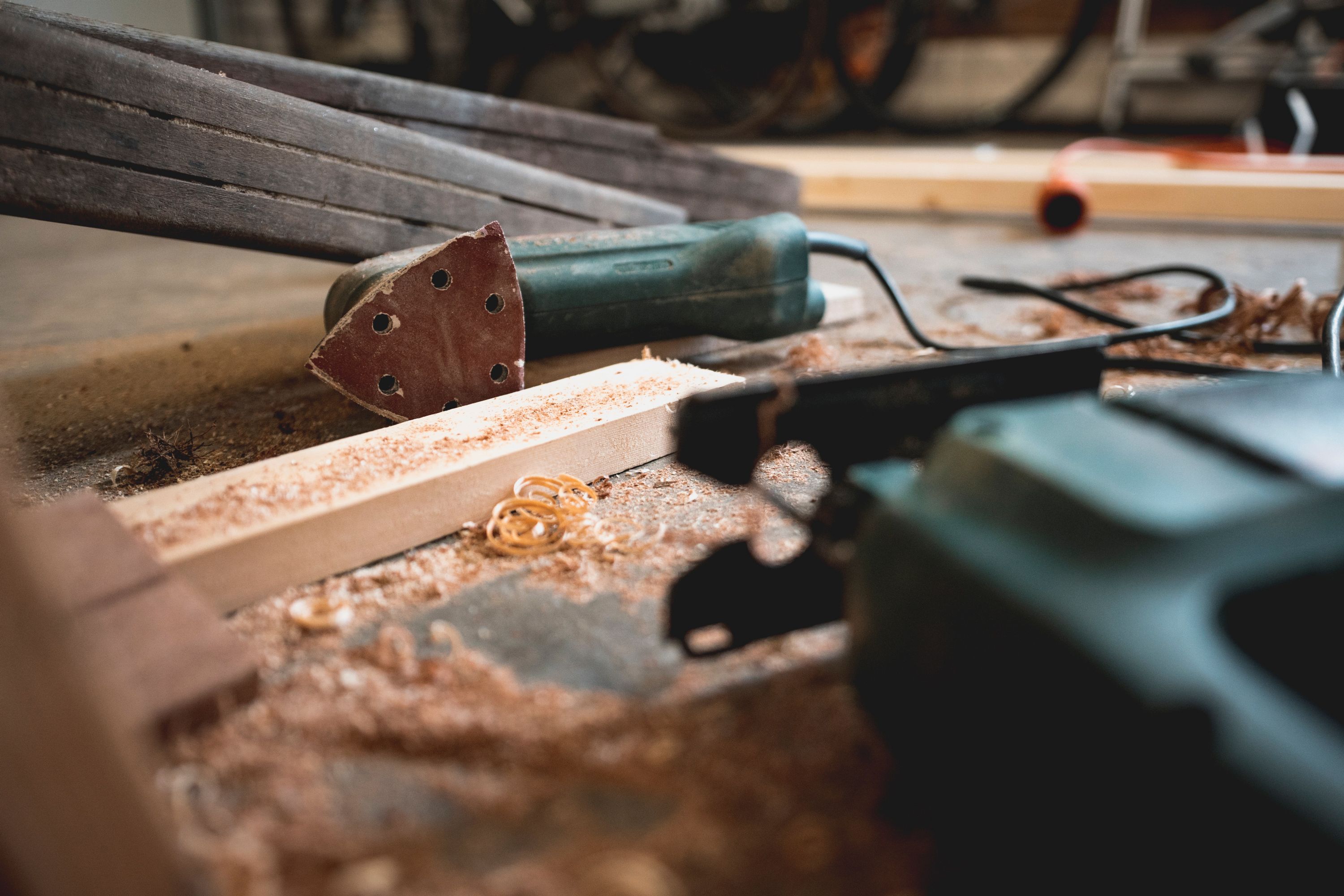 Discarded sander and pile of sawdust near electrical wire.