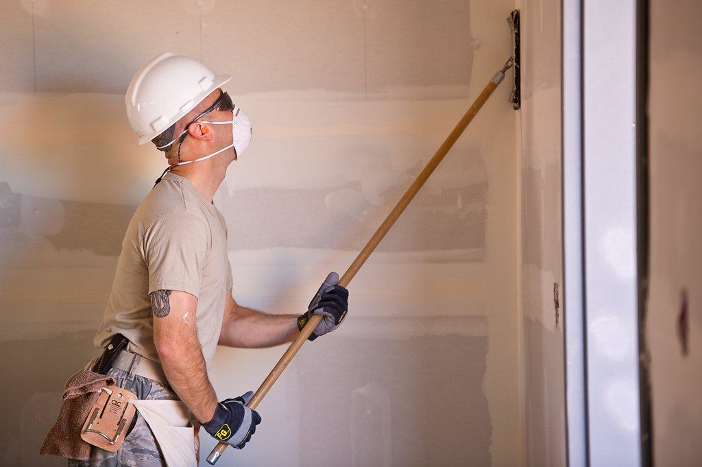 DIY enthusiast sanding a wall at home wearing protective gear