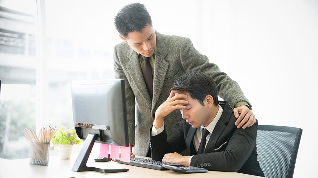 A male employee supports his co-worker by talking to him about stress