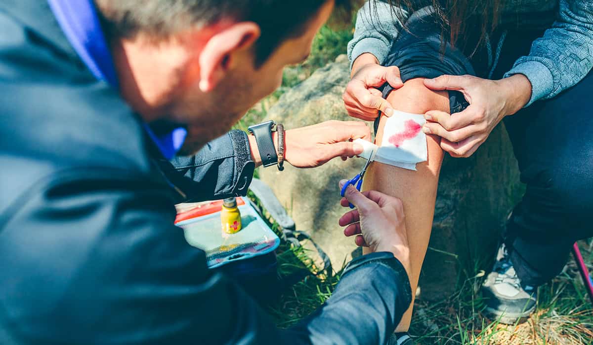 An image of someone dressing an injury outdoors