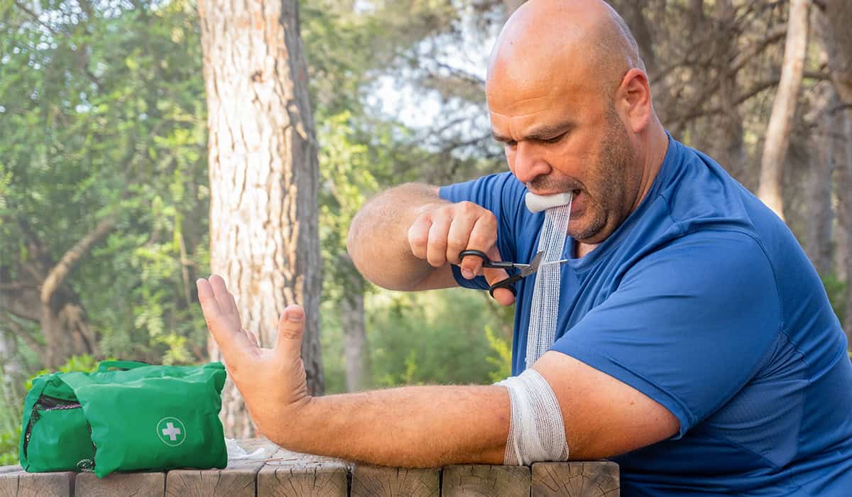 An image of someone wrapping a bandage around their arm while outside