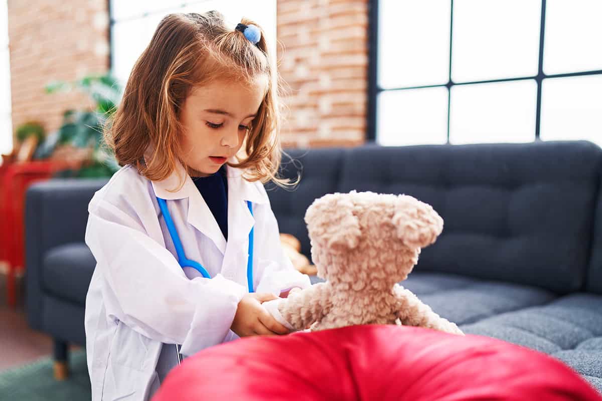 An image of a toddler with a bear and a toy stethoscope