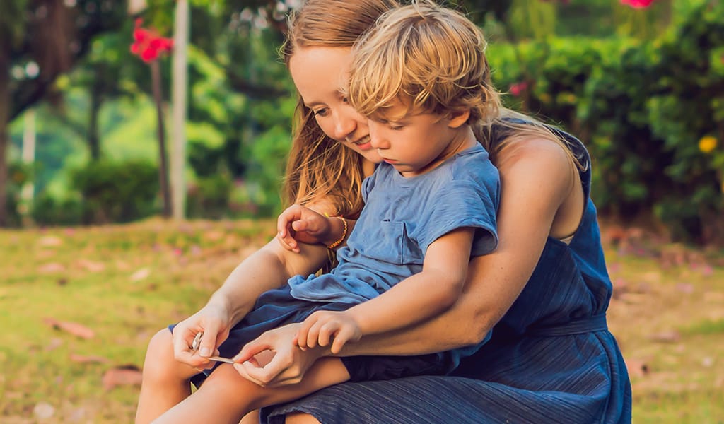 Mother applying a plaster to an injury on the knee of her young son 