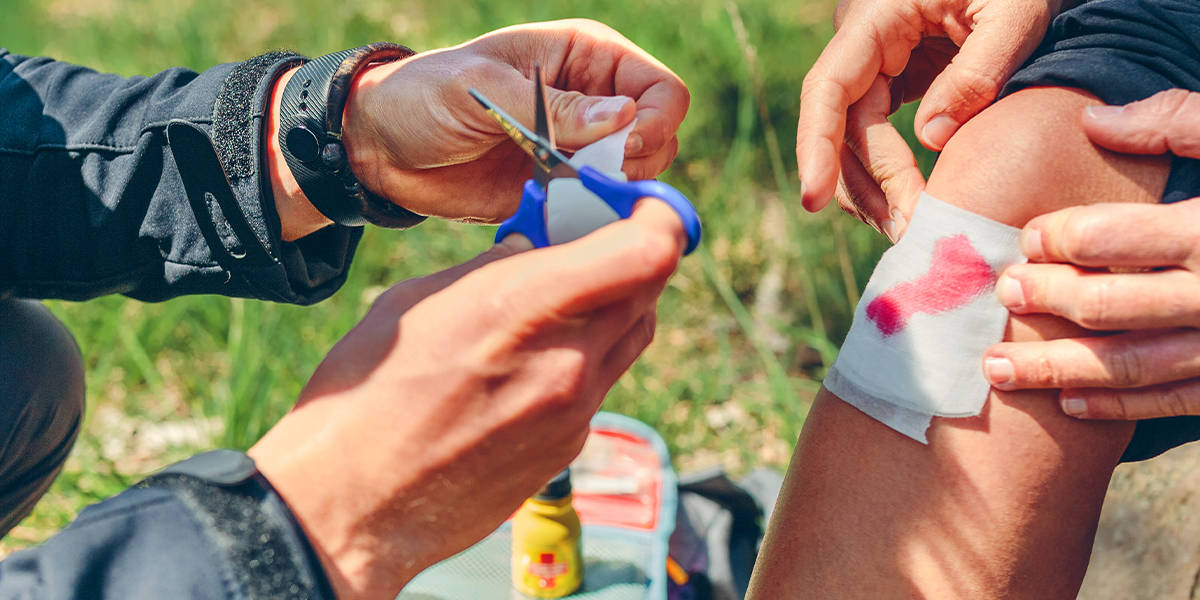 A first aider cutting a bandage to size