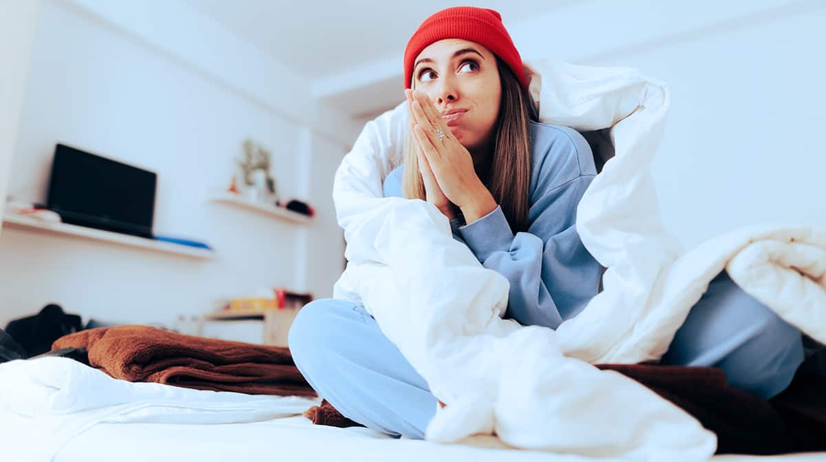 Woman keeping warm during the winter with heating and a blanket