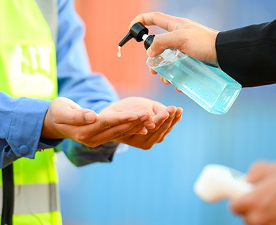 Person at construction site holds out hands for hand sanitising gel to reduce risk of COVID