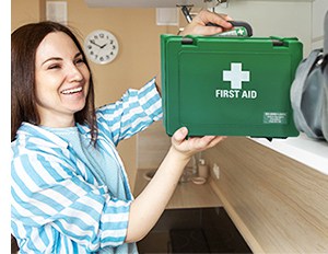 An adult places a home first aid kit safely in an accessible cupboard in the kitchen 