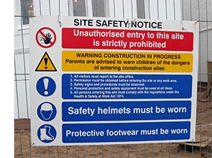 A site safety notice, attached to the fence of a building site, alerts employees to hazards and the precautions they need to take 